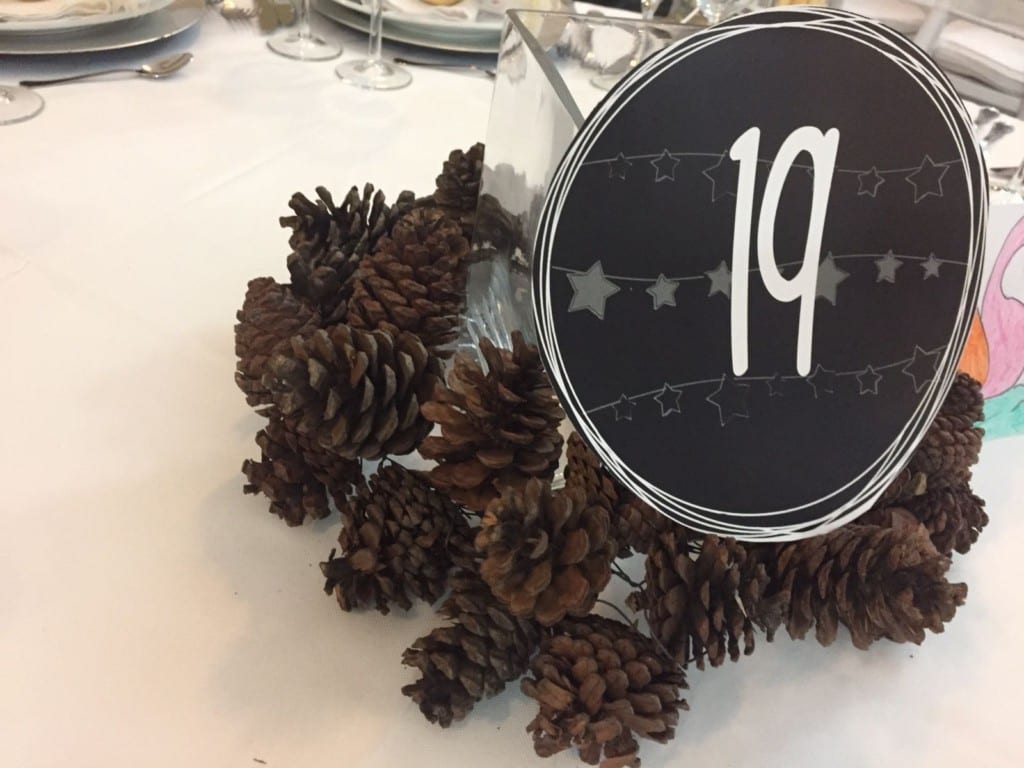 Centro de mesa navideño con piñas y número de mesa en una comida de empresa